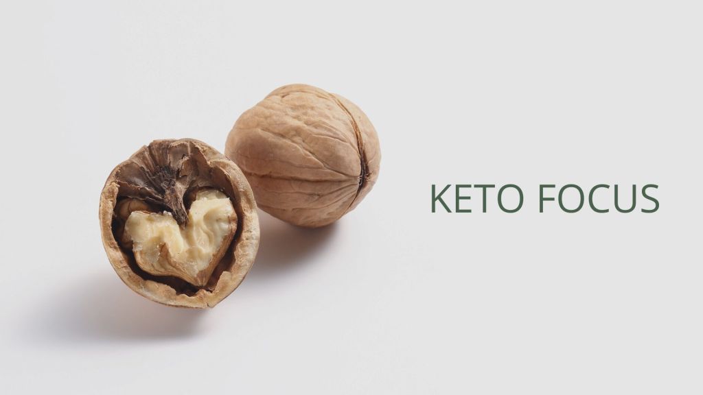 A walnut split open to reveal its heart-shaped kernel next to an unbroken walnut, accompanied by the text 'KETO FOCUS' on a white background.