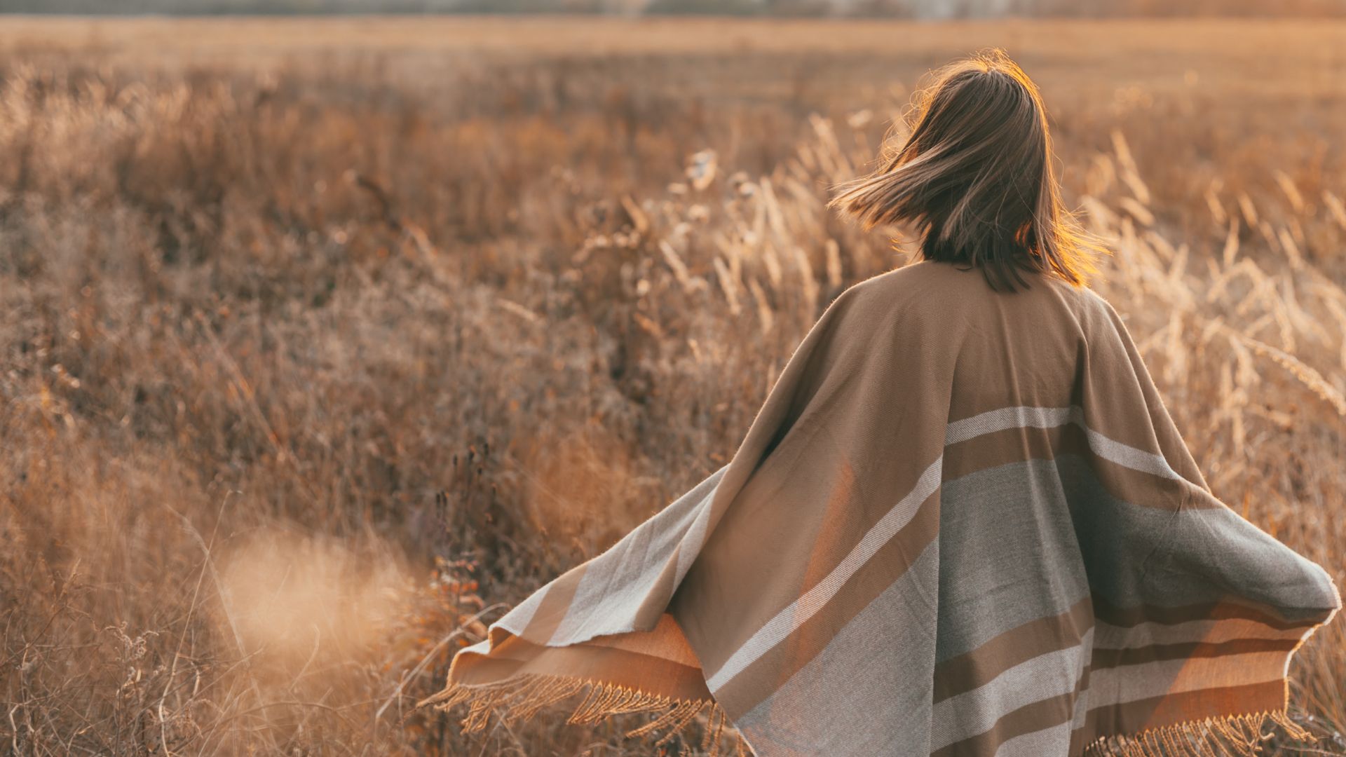 Vrouw midden 50 wandelt door een veld in de zon, symbool voor energie en balans tijdens de overgang met ondersteuning van keto.